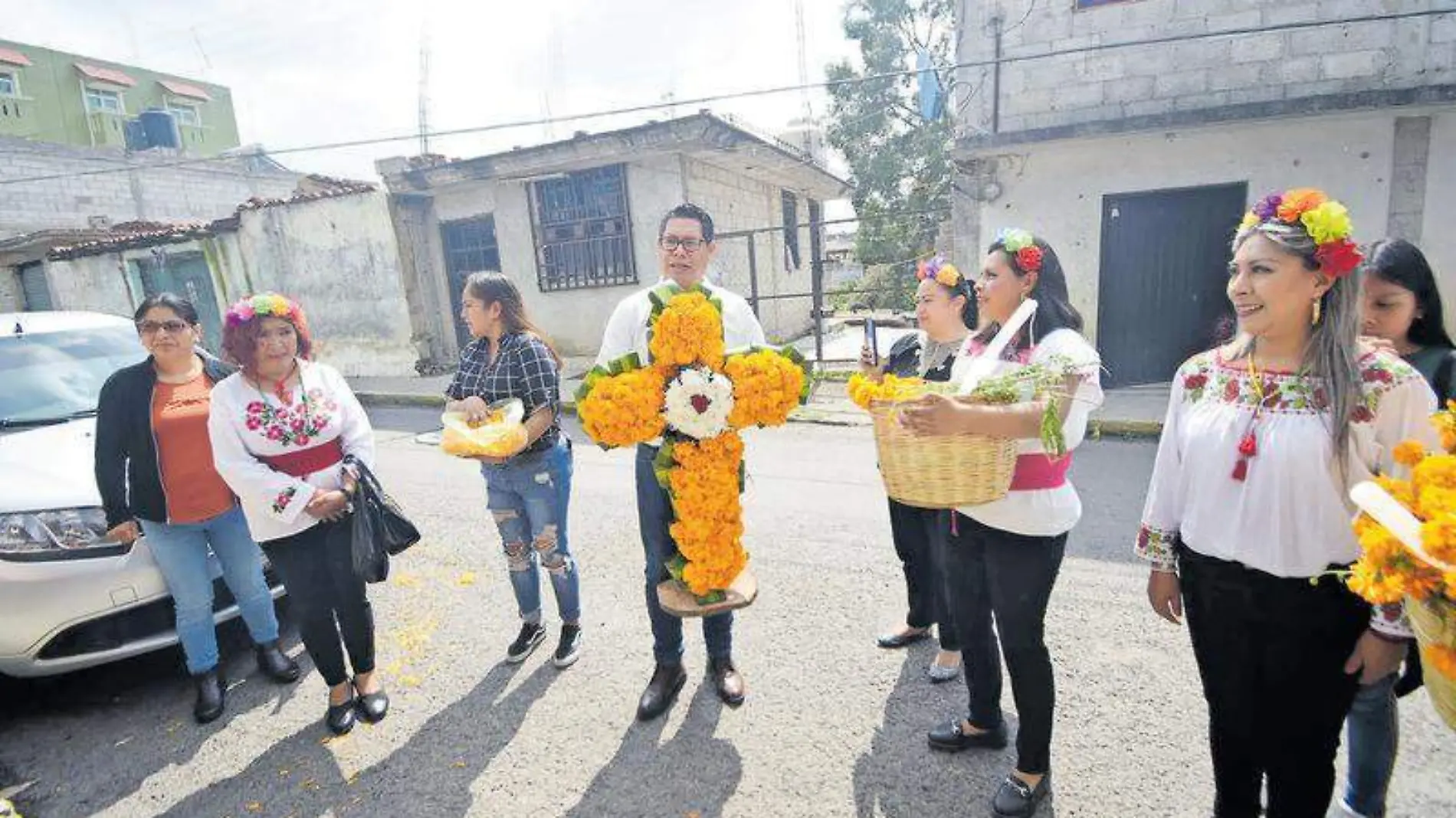 Los padrinos de la primera ofrenda entregan a los familiares de la persona que falleció una cruz adornada con flores de cempasúchil César Rodríguez